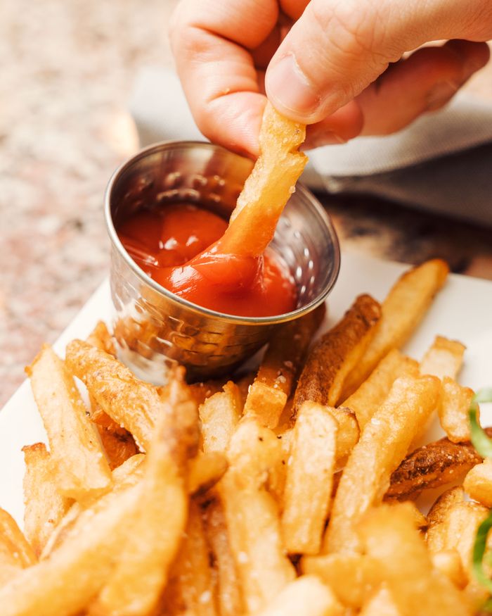 services-04 Close-up of crispy french fries being dipped into ketchup. Perfect fast food concept.