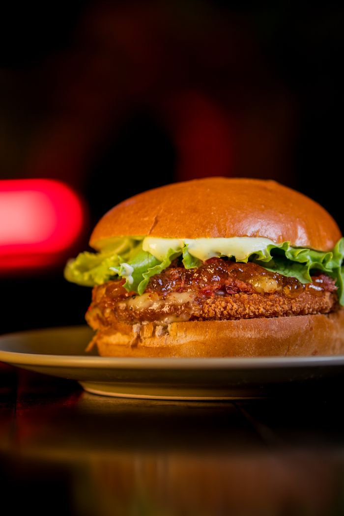 A close-up of a delicious gourmet burger with fresh lettuce and cheese on a bun.