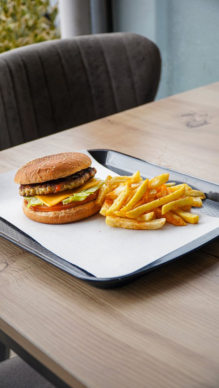 A delicious cheeseburger with fries served on a tray indoors in Niğde, Türkiye.