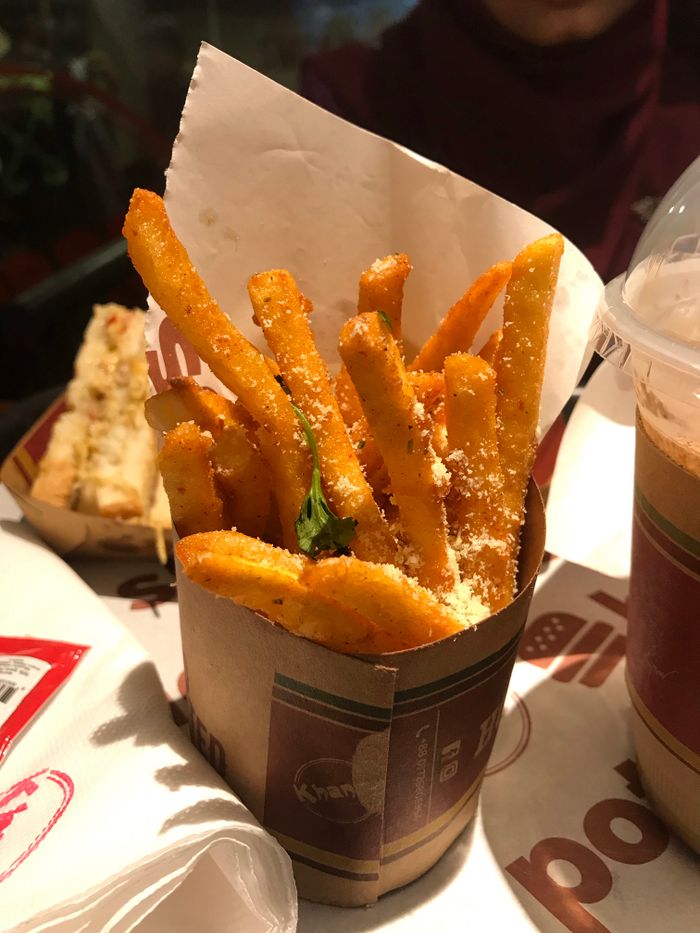 services-03 Crispy seasoned french fries served in a disposable cup with parmesan topping.